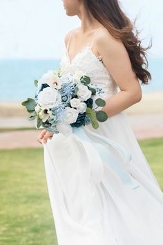 a woman in a white dress holding a blue and white bouquet