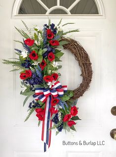 a wreath with red, white and blue flowers is hanging on the front door to welcome visitors