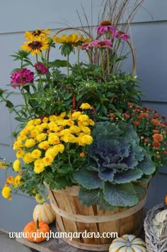 a basket filled with lots of colorful flowers next to pumpkins and gourds