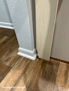 the corner of a room with wood flooring and white paint on the wall next to it