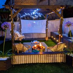 a fire pit in the middle of a backyard with chairs and lights on it's sides