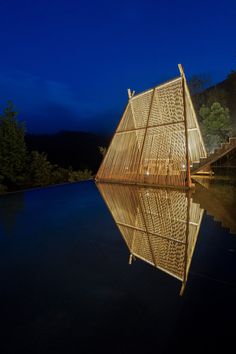 a wooden structure sitting on top of a body of water at night with lights reflecting in the water