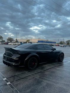 a black sports car parked in a parking lot on a cloudy day with dark clouds