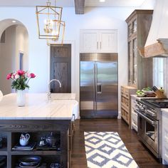 a kitchen with an island, refrigerator and stove top oven in it's center