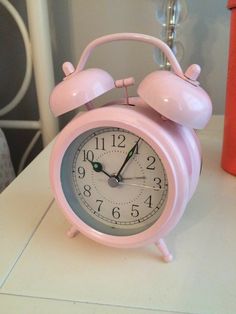 a pink alarm clock sitting on top of a white table