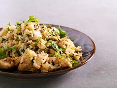 a brown plate topped with rice and meat covered in greens on top of a table