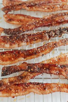 bacon strips sitting on top of a wire rack covered in seasoning sprinkles