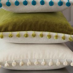 three pillows stacked on top of each other with tassels and pompoms