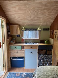 a kitchen area with sink, dishwasher and cabinets in the back ground next to a bed