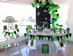 a table with green and black decorations on it in front of a window at a space themed birthday party