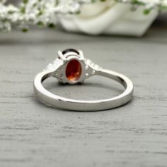 This beautiful ring is made from genuine 925 sterling silver with rhodium plating. Ring details- -The Main stone is an oval cut 8mm by 6mm Natural Garnet Stone -Side stones are 1.5 Round simulated diamonds -Ring is casted in solid 925 sterling silver with rhodium plating (yellow gold and rose gold plated also available, please check the drop down menu for more options) -The Total face height of the ring measures 8mms and the band width measures 2mms -Each ring is handmade and made to order, so p Silver Wedding Birthstone Ring With Polished Finish, Silver Birthstone Promise Ring With Polished Finish, Silver Birthstone Ring With Polished Finish For Promise, Topaz Ring With Polished Finish For Wedding, Anniversary Ruby Ring With Polished Finish And Open Design, Anniversary Ruby Ring With Polished Finish And Open Shape, Elegant Red Opal Ring For Anniversary, Silver Birthstone Ring With Polished Finish For Gift, Wedding Sterling Silver Cluster Ring With Polished Finish