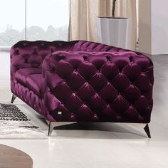 a purple couch sitting on top of a white rug