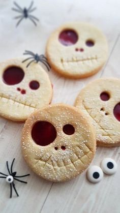 four cookies decorated like jack - o'- lanterns with googly eyes and spider webs