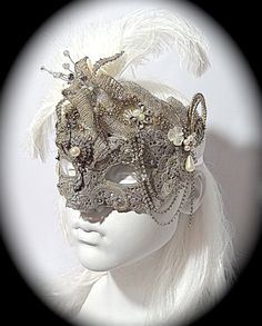 This opulent masquerade mask is platinum silver with lace overlays and gorgeous vintage rhinestone appliques that surround the top and cheeks. A vintage jewelry piece and a silver beaded flower are center on the forehead. The molded mask is loaded with rhinestones, gems, and vintage bead accents. Pearl drops & loops of rhinestone chain add elegant touches to this Art Deco style mask. Sprays of white ostrich feathers frame the top and one ear. It ties with white satin ribbons in back and is f Elegant Headpieces For Masquerade Carnival, Elegant Headpieces For Carnival Masquerade, Silver Rhinestone Eye Masquerade Mask, Silver Rhinestone Eye Mask For Masquerade, Elegant Eye Mask Masquerade For Costumes, Silver Fantasy Costume Mask, Silver Fantasy Carnival Mask, Elegant Eye Mask For Masquerade Costume, Silver Fantasy Masks And Prosthetics For Masquerade