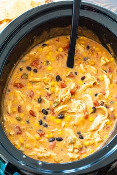 a crock pot filled with chicken and black bean soup next to tortilla chips