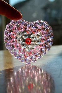 a heart shaped brooch sitting on top of a table next to a person's hand