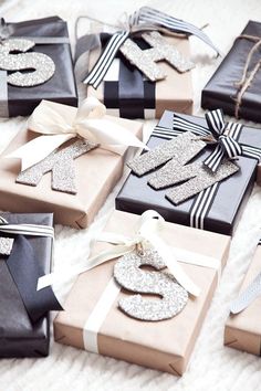 many presents are wrapped in black and white paper with silver glitter numbers on the top