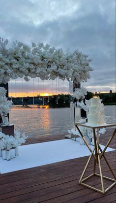 an outdoor wedding setup with flowers and candles on the table next to water at sunset