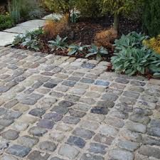 an outdoor walkway made out of cobblestones with plants and trees in the background