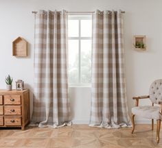 a living room with a chair, window curtain and wooden dresser in front of it