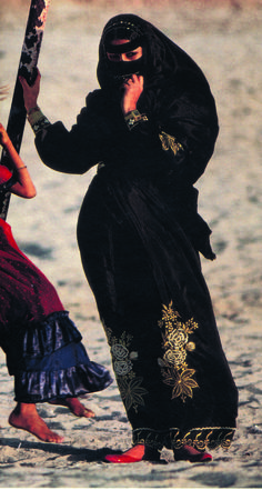 two women dressed in black and red on the beach