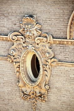 an ornately carved mirror on the side of a brick wall