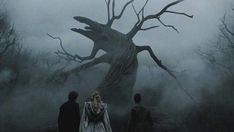 two people standing in front of a creepy tree