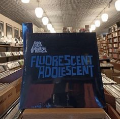 a record store with several records on the shelves and an advertisement for fluorescent adolescent