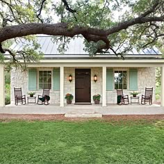 a house with rocking chairs in front of it and a large tree overhanging the porch