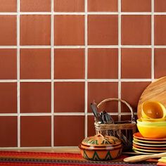 colorful dishes and utensils are arranged on a table in front of a tiled wall