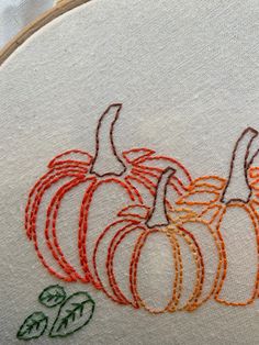 three pumpkins on a white background with orange and green stitching in the middle