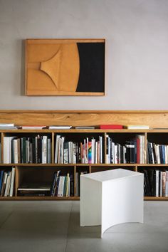 a bookshelf filled with lots of books next to a white box on the floor