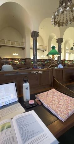 an open book sitting on top of a table next to a laptop computer and notebook