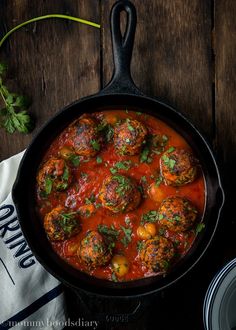 a skillet filled with meatballs covered in sauce and garnished with parsley