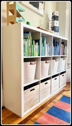 the bookshelf is filled with lots of books and storage bins on it