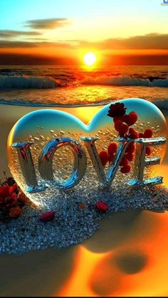 the word love is made up of flowers and sand at the beach as the sun sets