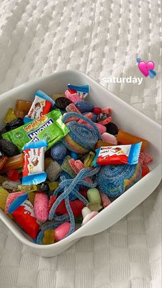 a white bowl filled with candy on top of a bed