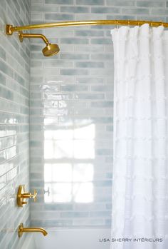 a bathroom with blue and white tiles, gold fixtures and a shower curtain in the corner