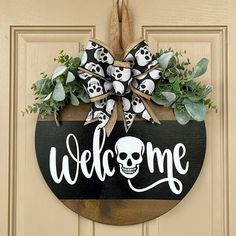 a welcome sign hanging on the front door with skulls and bones painted on it's side