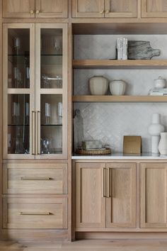 a wooden cabinet with glass doors and shelves filled with dishes, vases and other items