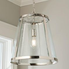 a light fixture hanging from the ceiling in a room with white walls and trimmings