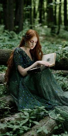 a woman sitting in the woods reading a book with her long red hair pulled back