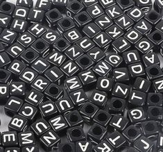 black and white alphabet beads with letters on the end are scattered together in an array