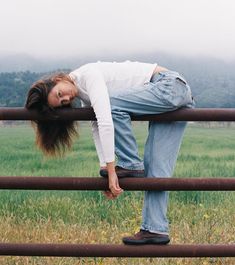 a woman leaning on a fence with her head in the ground and hands behind her back