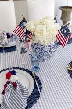 a patriotic table setting with blue and white plates, napkins, and flowers in a vase