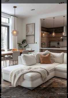 a living room filled with furniture next to a kitchen and dining room table in front of a large window