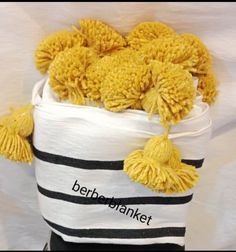 a white bucket filled with yellow pom - poms