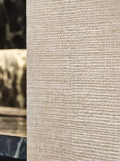 a close up view of the textured fabric on a table top with a vase in the foreground