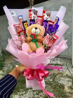 a teddy bear is holding a bouquet of chocolates and candy bars in it's hand