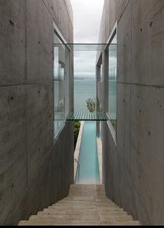 the stairs lead up to an indoor swimming pool that is built into concrete walls with glass balconies on each side